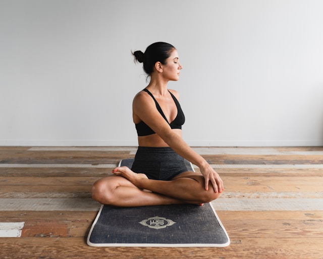 image shows a woman doing yoga at home she is in an easy crossed legged position on her yoga mat blog post is about starting a home yoga practice