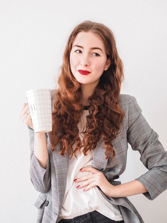 picture showing woman with long hair wearing red lipstick dressed in business clothes and holding a coffee cup having a successful day best Sunday routine