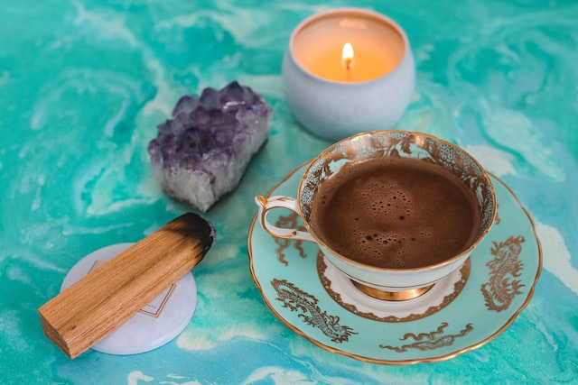 image showing candle, crystal, palo santo and cup of hot chocolate new moon affirmations