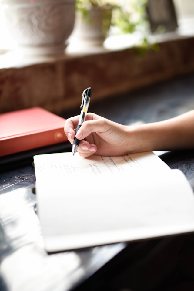 image shows close up of a notebook and female hand blog post is about how to live an intentional life do regular check ins