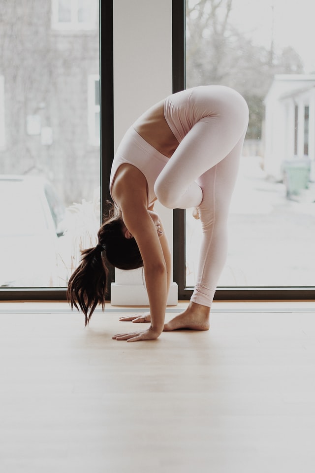 young woman doing yoga at home standing pigeon pose yoga for grief