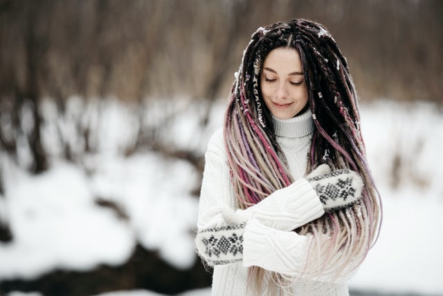 woman with long tread locks brown hair in winter countryside going for a walk in the snow 12 self-care ideas for winter