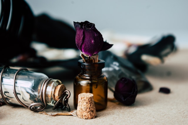 image showing small empty glass bottles one glass bottle filled with a dark red rose decorations of ritual essentials full moon affirmations