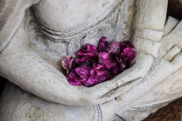 image showing close up of grey stone buddha holding purple flower leaves in his hands gratitude activities for adults