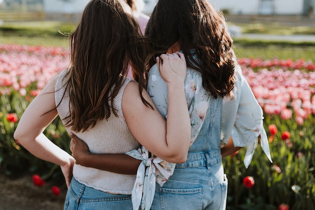 image showing two friends from the back looking at a flower field, friends are both female, friends are hugging gratitude activities for adults