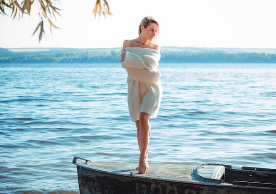 woman wearing white knitted dress standing on boat in lake 12 refreshing self-care ideas for spring