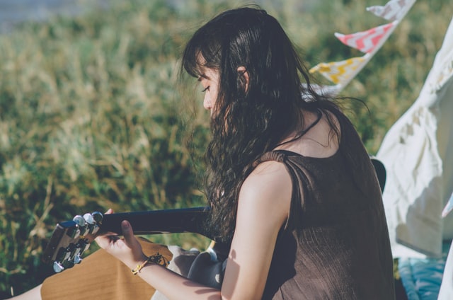 woman playing guitar in nature self-care ideas for spring