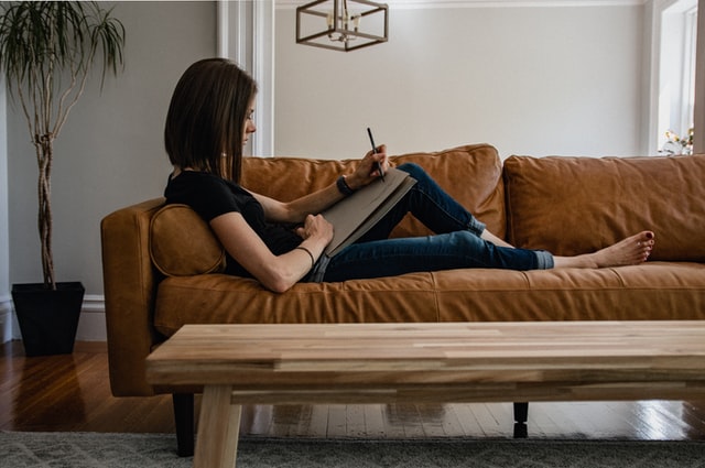 woman sitting on couch taking notes how to declutter your life