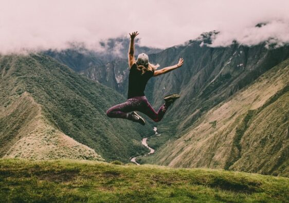 woman jumping up in the air overlooking mountains happiness 10 healthy lifestyle habits