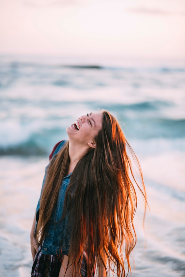 woman with long brown hair at beach laughing 10 healthy lifestyle habits for busy women