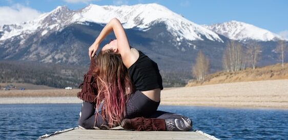 girl doing mermaid yoga pose on pier in front of mountains 11 reasons why you should start yoga
