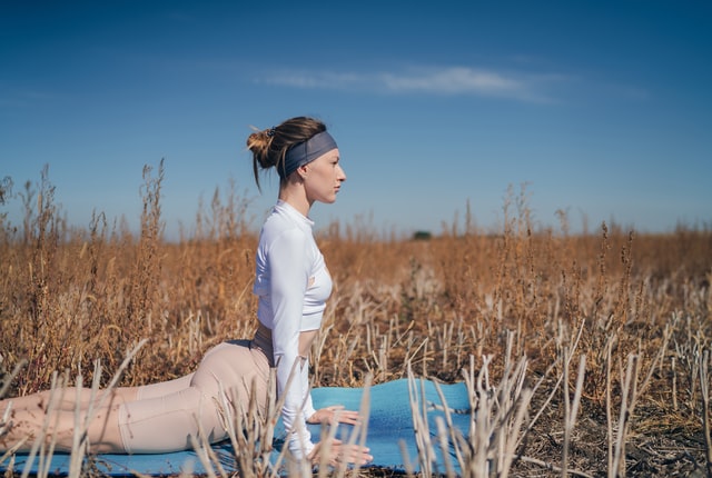 blonde woman in field on yoga mat upward facing dog 11 reasons why you should start yoga