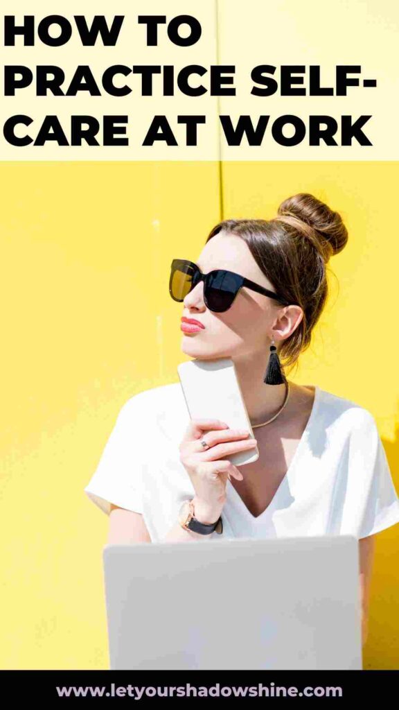 woman wearing big black sunglasses standing in front of a yellow wall holding a mobile phone how to practice self-care at work