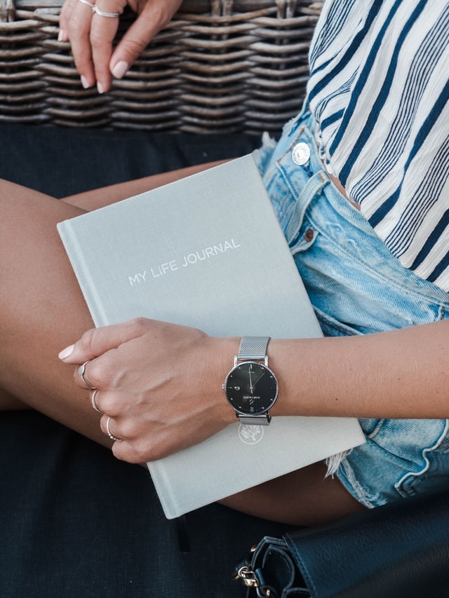 woman holding a journal in her hand 12 self-care ideas for summer journaling