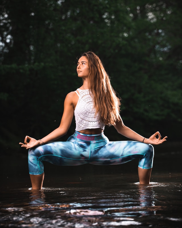 image showing woman in goddess yoga pose woman standing in water in forrest environment how to choose a yoga retreat