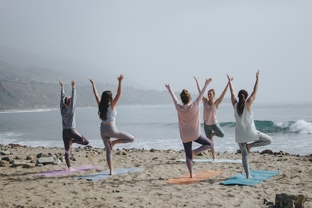 image showing group of people doing yoga at the beach with ocean in the background how to choose a yoga retreat that is right for you