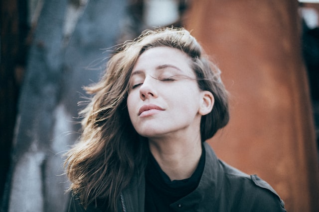 woman with long brown hair outside taking a deep breath 11 easy ways to relax when stressed