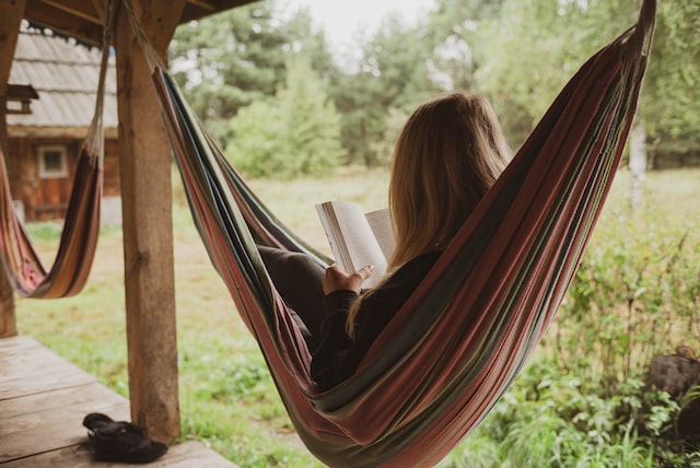woman in hammock reading a book outside on veranda 11 easy ways to relax when stressed