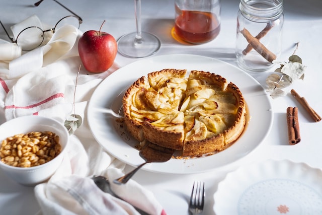 freshly baked apple pie standing on table surrounded by apples, cinnamon sticks and tea 12 self-care ideas for autumn casual Sunday afternoon tea