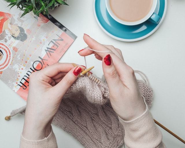 close up of women hands with red nail polish knitting 12 self-care ideas for autumn