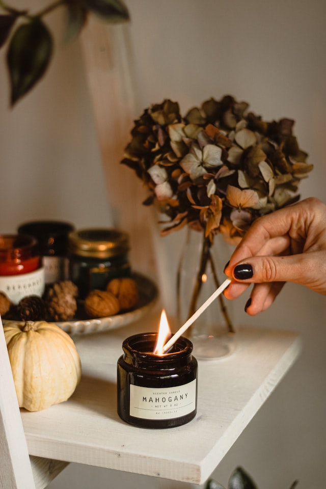 close up of female hand lighting candle 12 self-care ideas for autumn