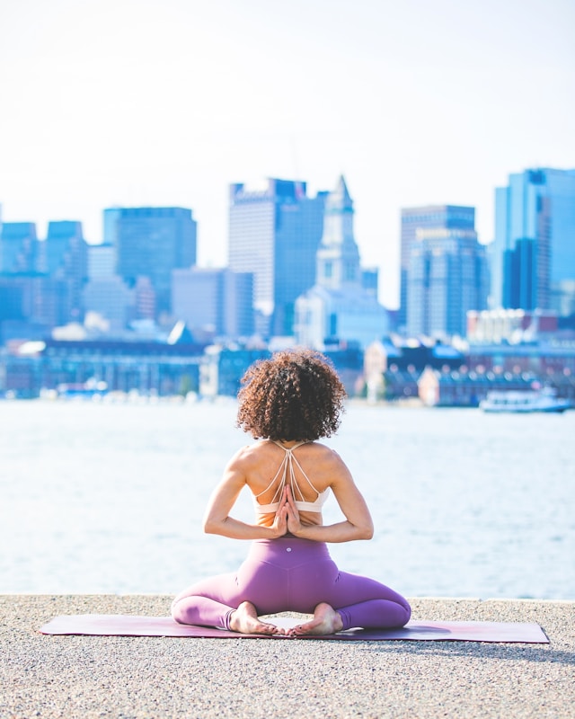 image shows a woman doing morning yoga with a city skyline in the background blog post is about how yoga helps to boost the immune system