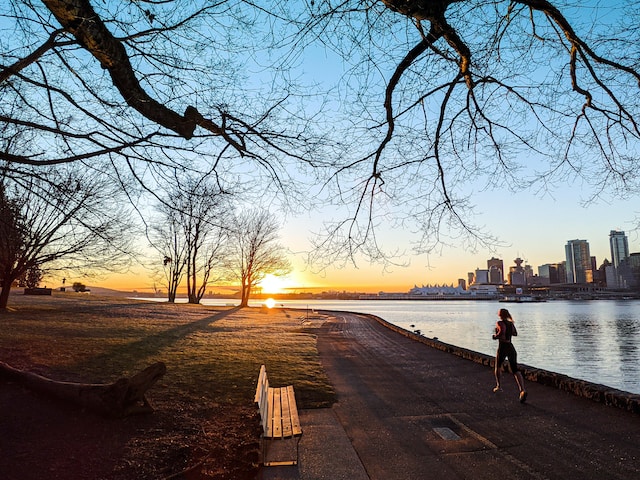 image is showing a woman running along a river in the background is the skyline of a city blog post is about coping with the holidays keep up your healthy habits