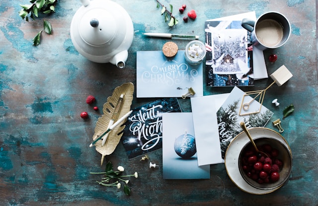 image shows a table filled with tea and happy holiday cards blog post is about navigating the holiday season