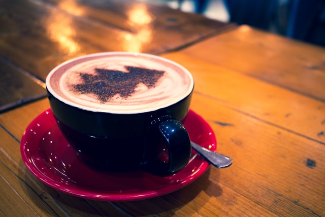 image shows a close up of a cup of coffee with a Christmas tree created by a barista blog post is about navigating the holiday season