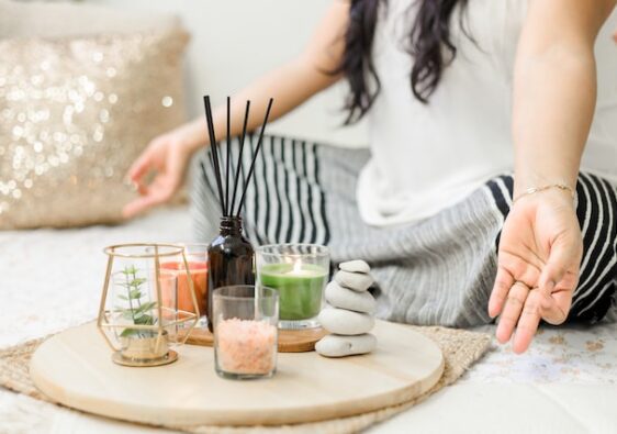 close up of woman meditating with zen items such as candles and incense sticks in front of her