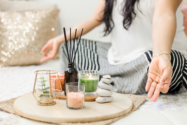close up of woman meditating with zen items such as candles and incense sticks in front of her