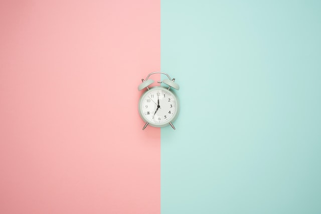 image showing white alarm clock displayed on pastel background colour how to start journaling