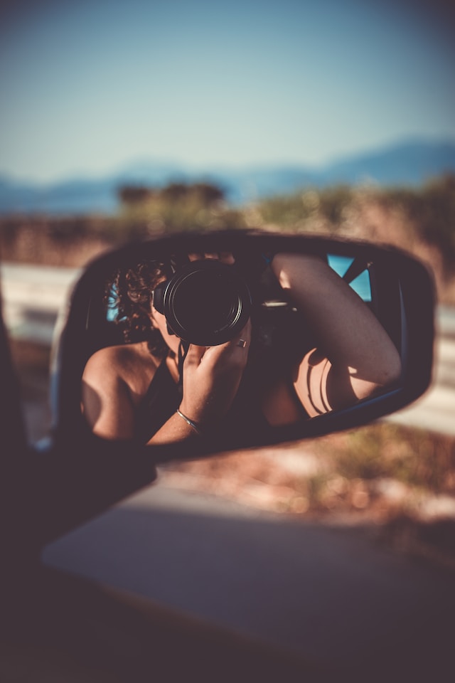 woman sitting in car taking picture of her own reflection in the outside mirror of car how to start journaling
