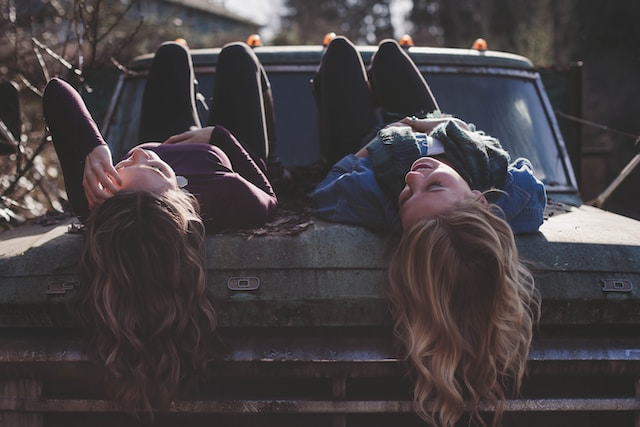 two friends, women lying on top of car looking at sky talking how to cultivate self-love set healthy boundaries