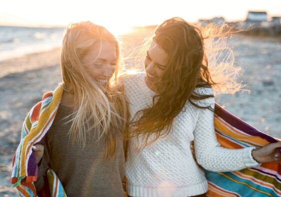 image showing two women in nature beach setting going for a walk and laughing how to set healthy boundaries