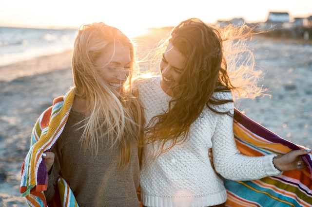 image showing two women in nature beach setting going for a walk and laughing how to set healthy boundaries