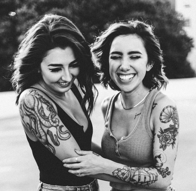 black and white image of two tattooed women in nature setting laughing how to set healthy boundaries