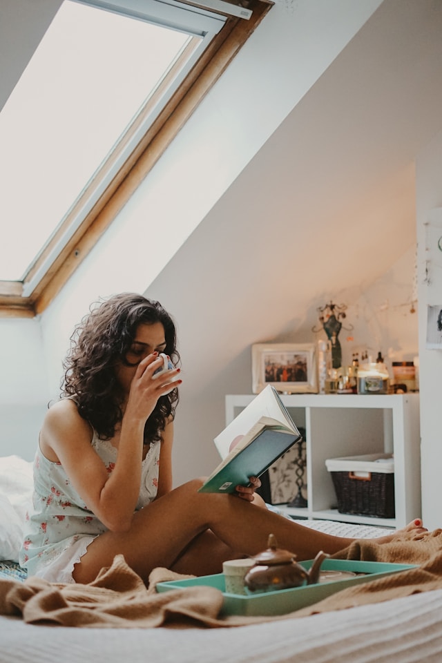 image showing woman at home sitting bed, reading a book enjoying a self care moment pamper yourself