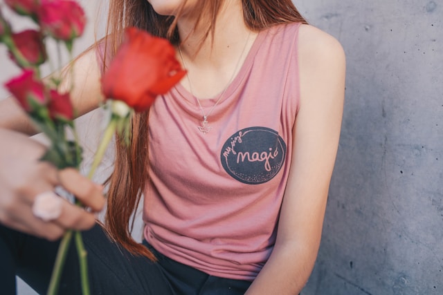 image shows a close up of a woman's upper body and the woman holds a bunch of roses in her hand the blog post is about self-love exercises