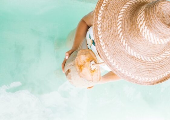 picture showing woman wearing hat drinking coconut walking in pool from top perspective treat yourself