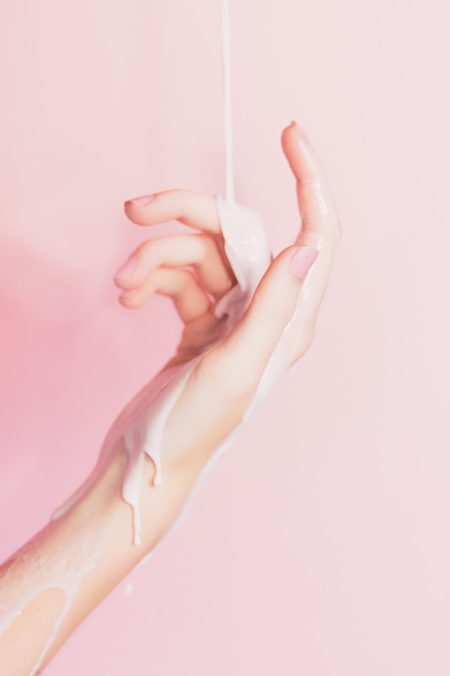 close up of female hand against pink background lotion running down treat yourself ideas home spa