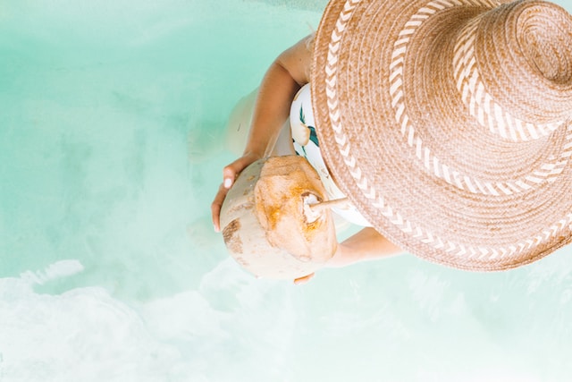 picture showing woman wearing hat drinking coconut walking in pool from top perspective treat yourself