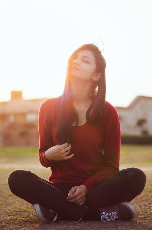 the picture shows a woman sitting on the grass taking a few deep breaths the blog post is about ways to pamper yourself and powerful pamper yourself ideas