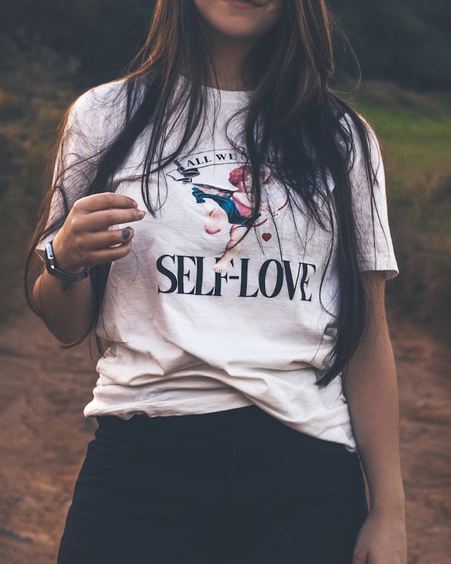 image showing a close up of a woman's upper body and the woman is wearing a t-shirt with a print about self love blog post is about affirmations for self love