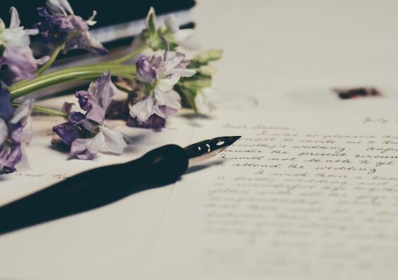 close up of journal with ink pen and flower decoration next to the journal daily gratitude journal prompts