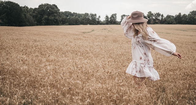 women with long blonde hair wearing beige hat and white dress walking in field self-love affirmations