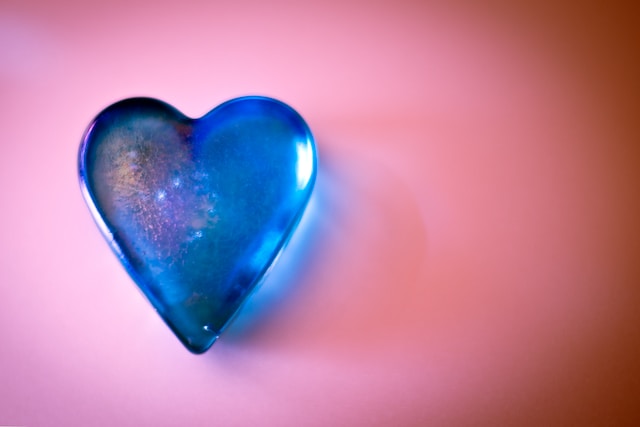 image showing blue heart made of glass displayed on a pink background nicely lit self-love affirmations