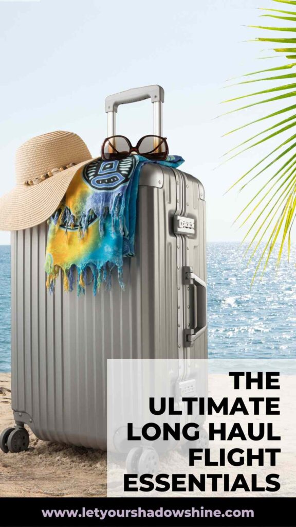 picture showing suitcase at the beach with scarf, hat and sunglasses on display long haul travel essentials