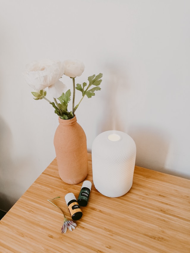 picture showing white diffuser on wooden table with flowers next to it ways to relax after work aromatherapy