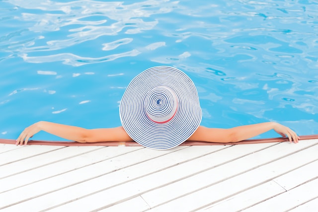 image showing woman from the back wearing a big white hat in a pool relaxing ways to relax after work